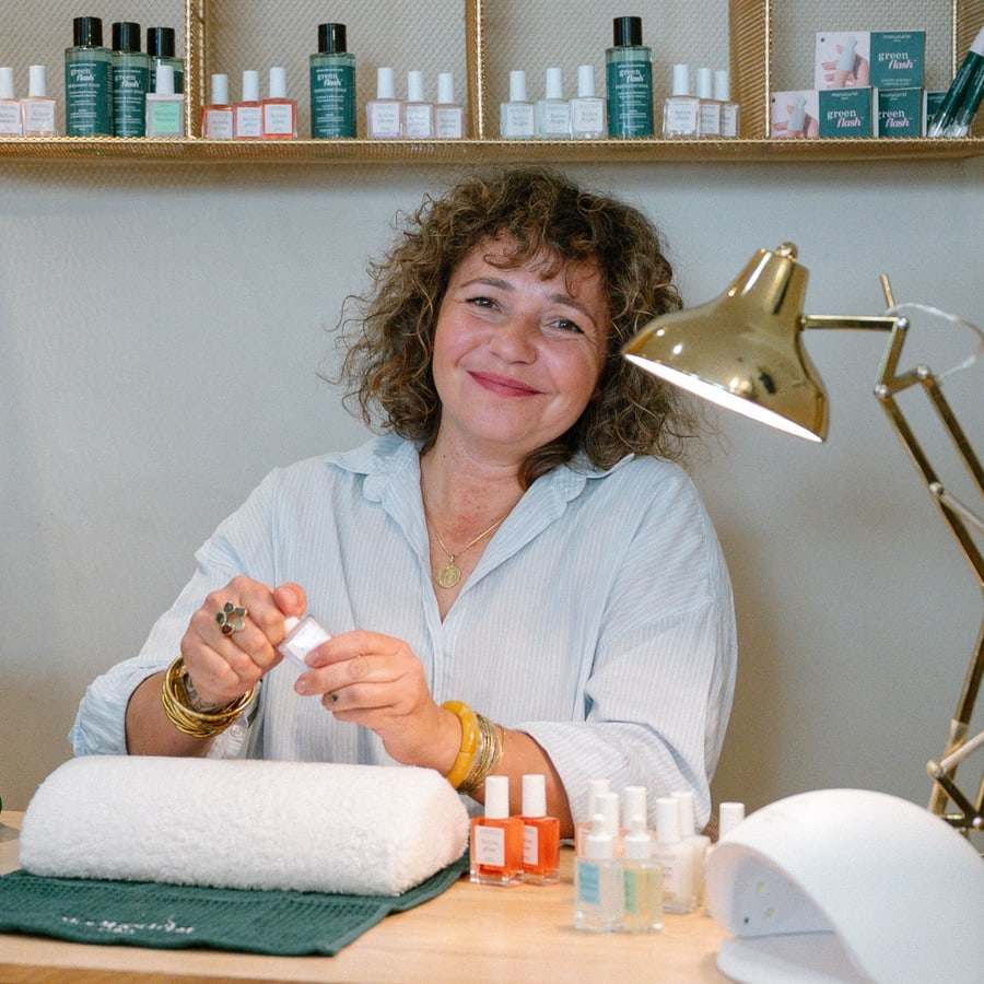 Aurélie sourit, un flacon de vernis à la main, au corner onglerie de Quand fond la neige