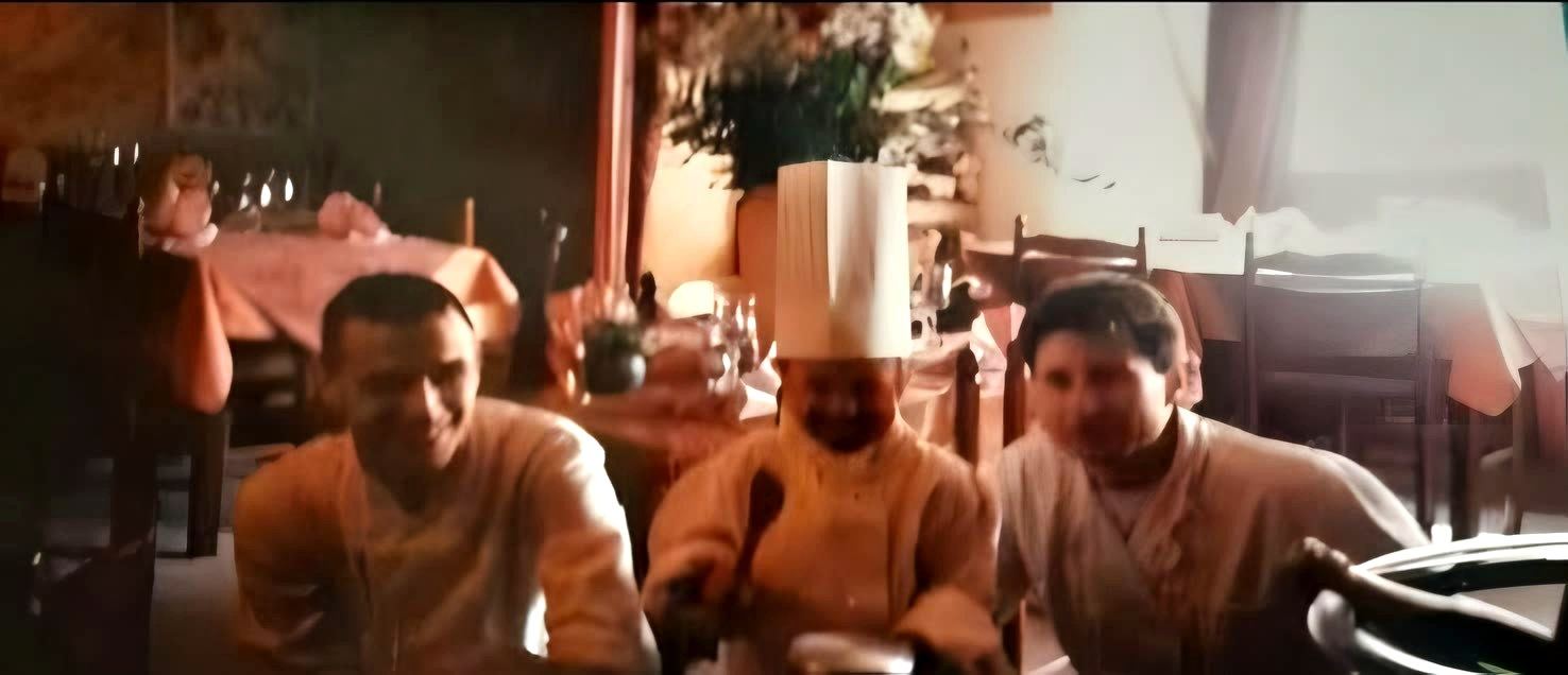 Photo d’enfance : une petite cuisinière en toque entre deux cuisiniers, dans la salle d’un restaurant