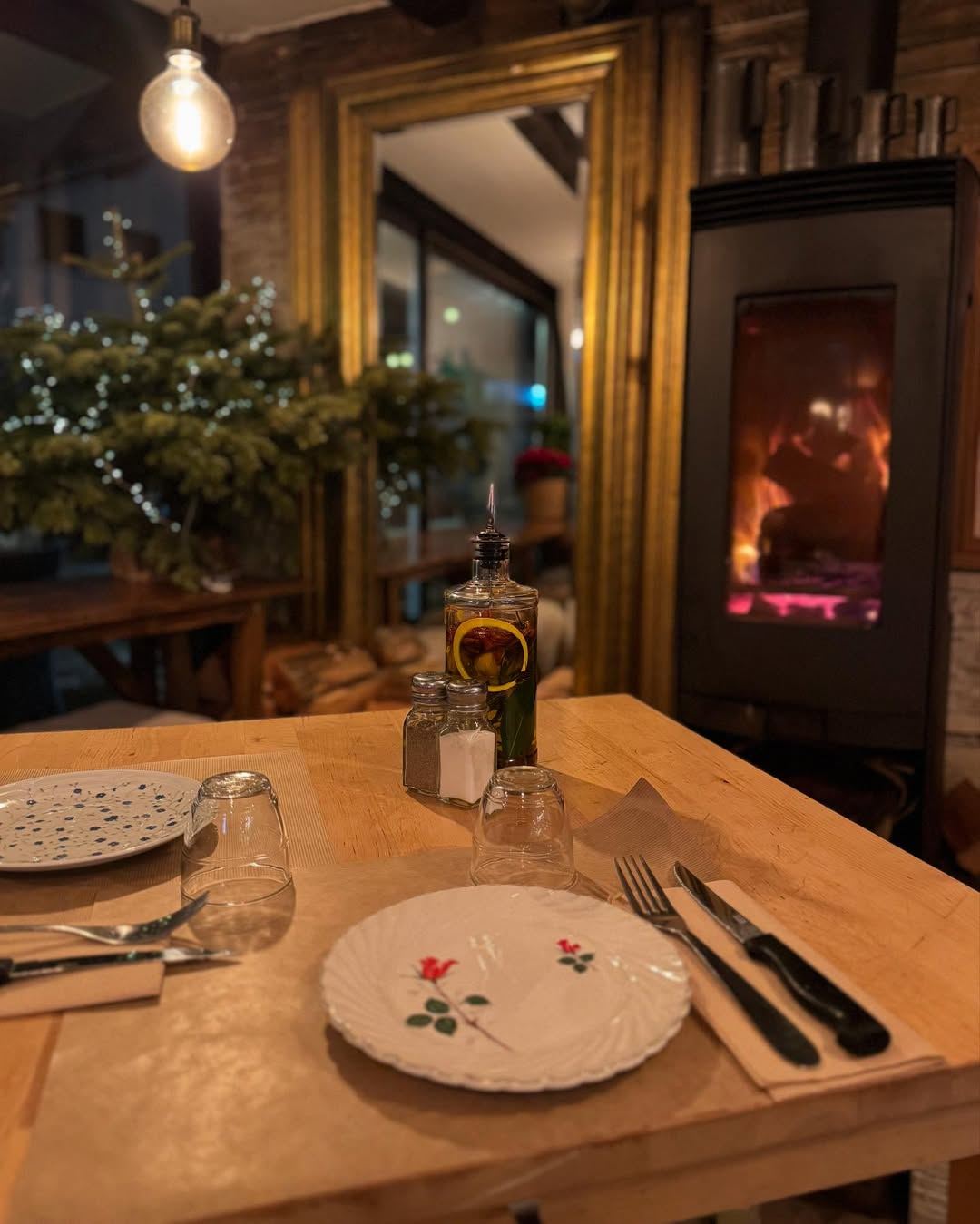 La salle de La Maison le soir, une table dressée devant le poêle à bois allumé