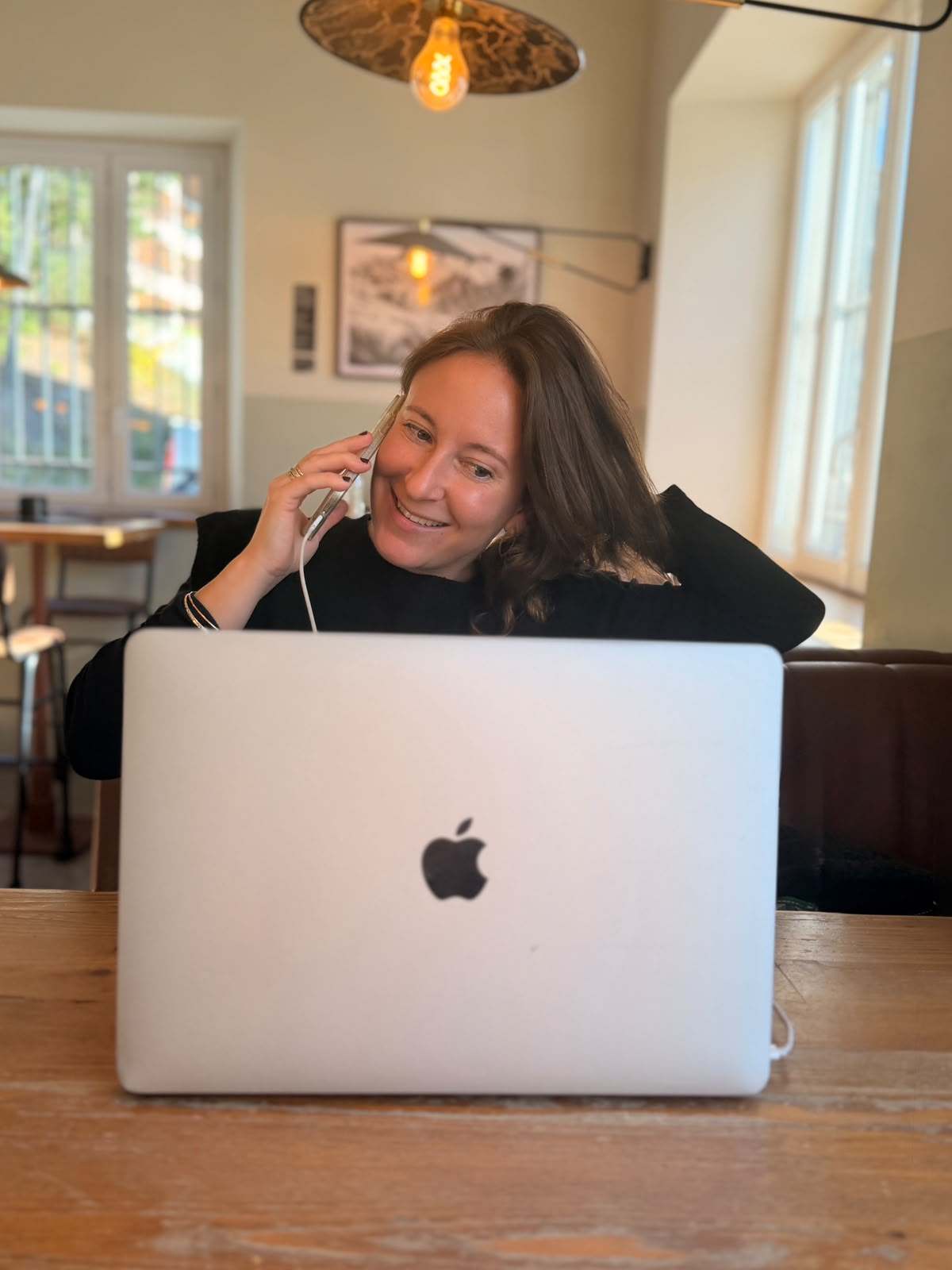 Laure au téléphone, le sourire aux lèvres, derrière son ordinateur portable