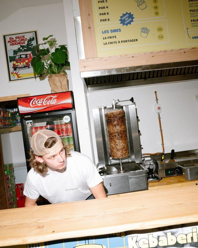 Un cuisinier du Rond-Point accoudé au comptoir, sous les menus jaunes