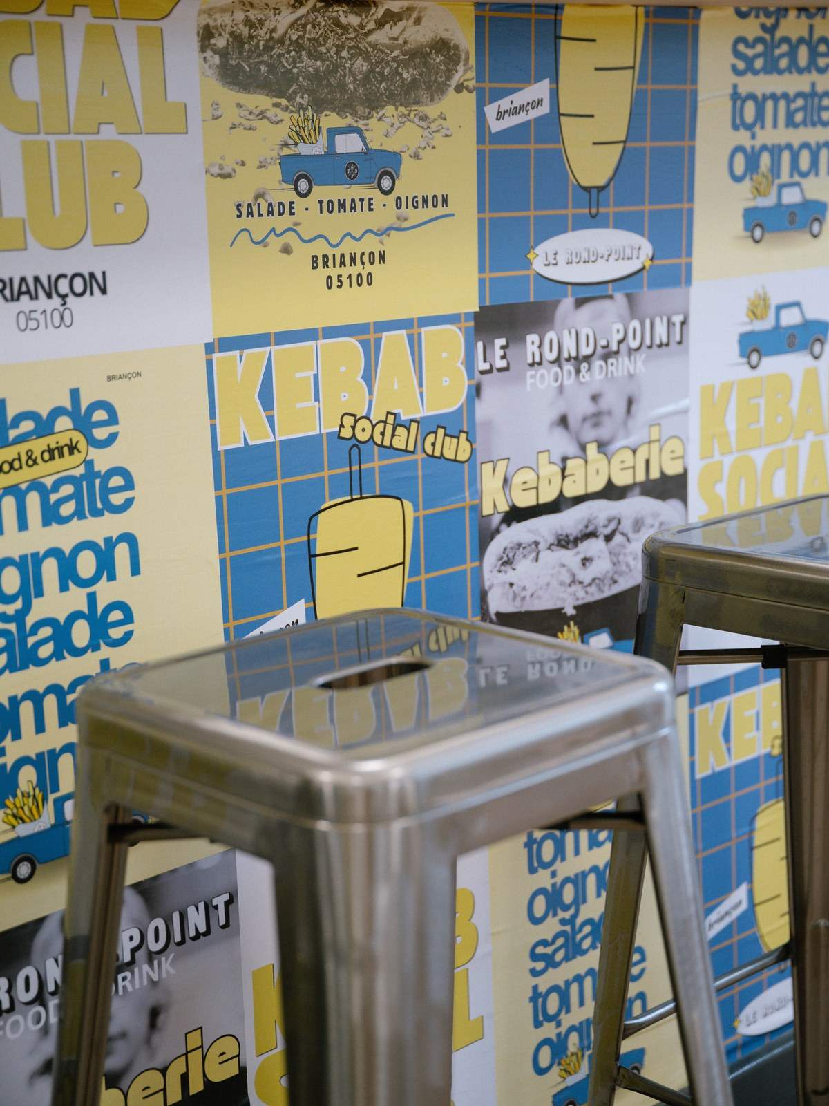 Affiche du Rond-Point : les murs « Kebab Social Club » jaunes et bleus et un tabouret en métal