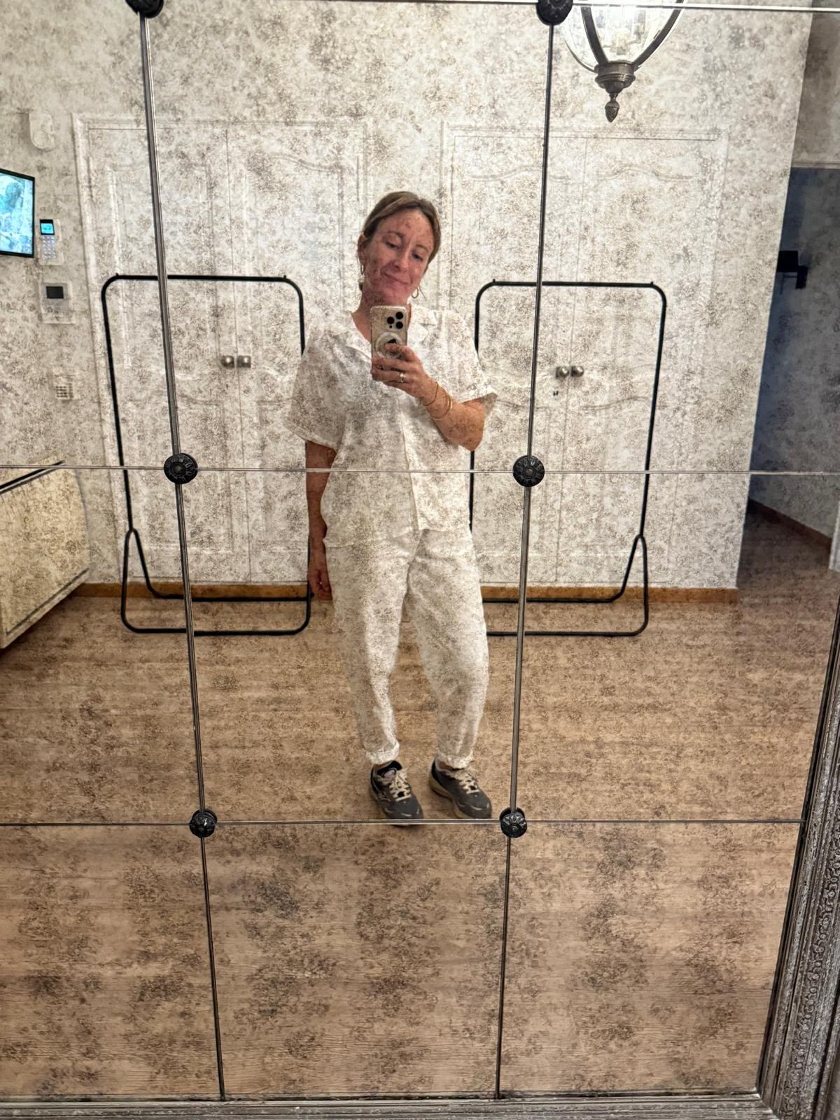 Laure en tenue de service se photographie dans un grand miroir de la villa