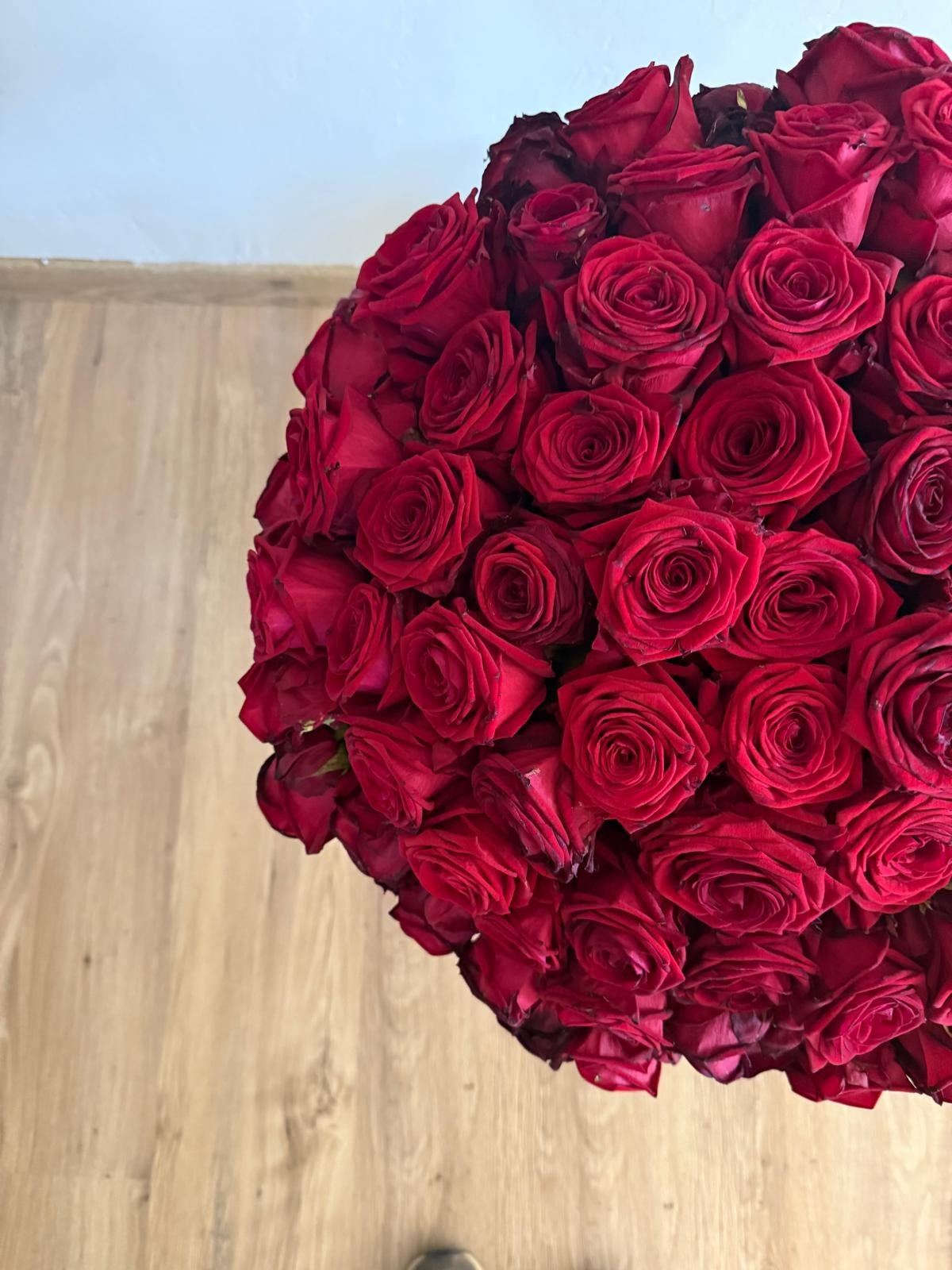 Un grand bouquet de roses rouges vu d’en haut, sur un parquet clair