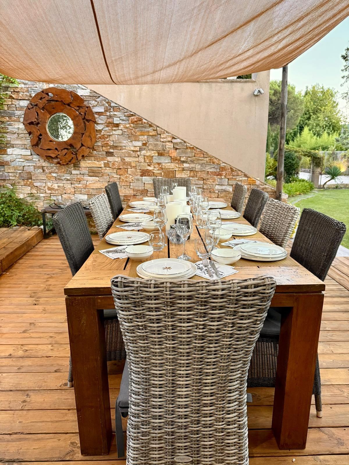 Une longue table dressée sous une voile d’ombrage, dans le jardin d’une villa de Saint-Tropez