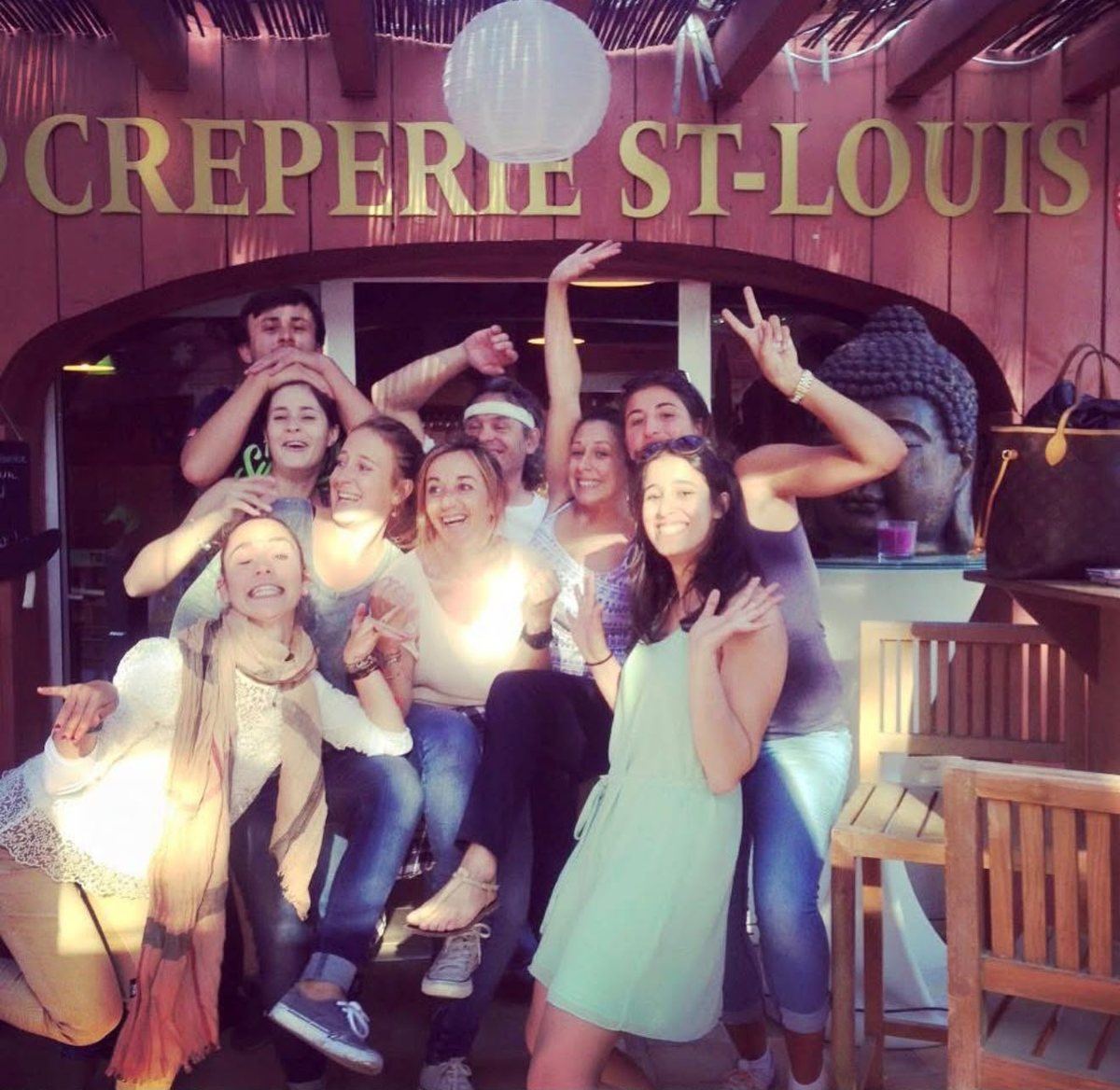 L’équipe de la Crêperie Saint-Louis, bras en l’air sous l’enseigne