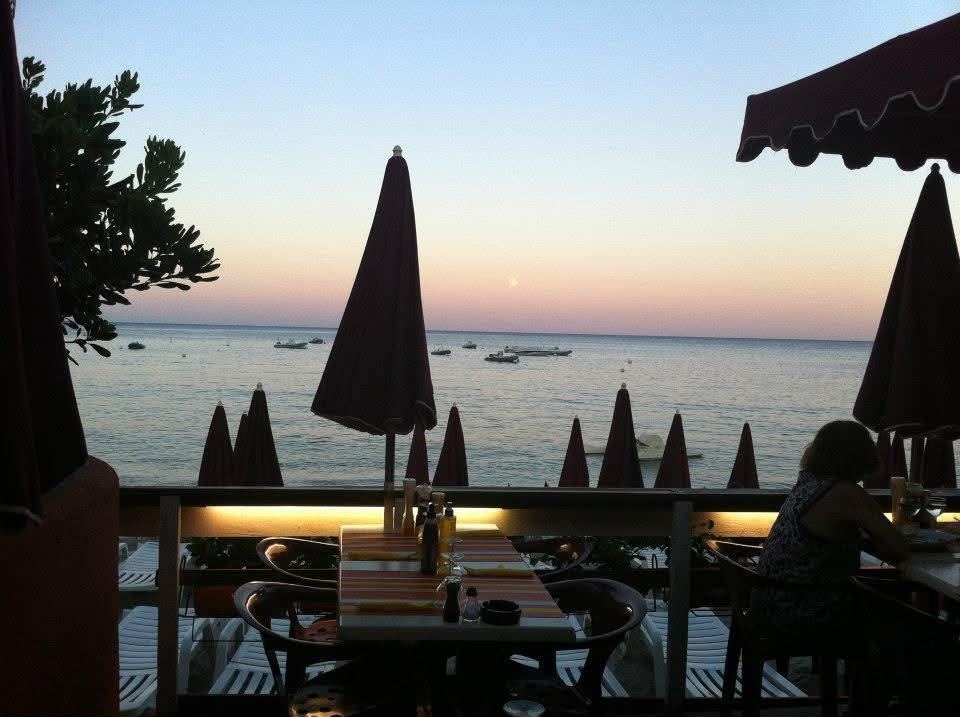 Une terrasse de restaurant face à la mer au coucher du soleil, parasols fermés
