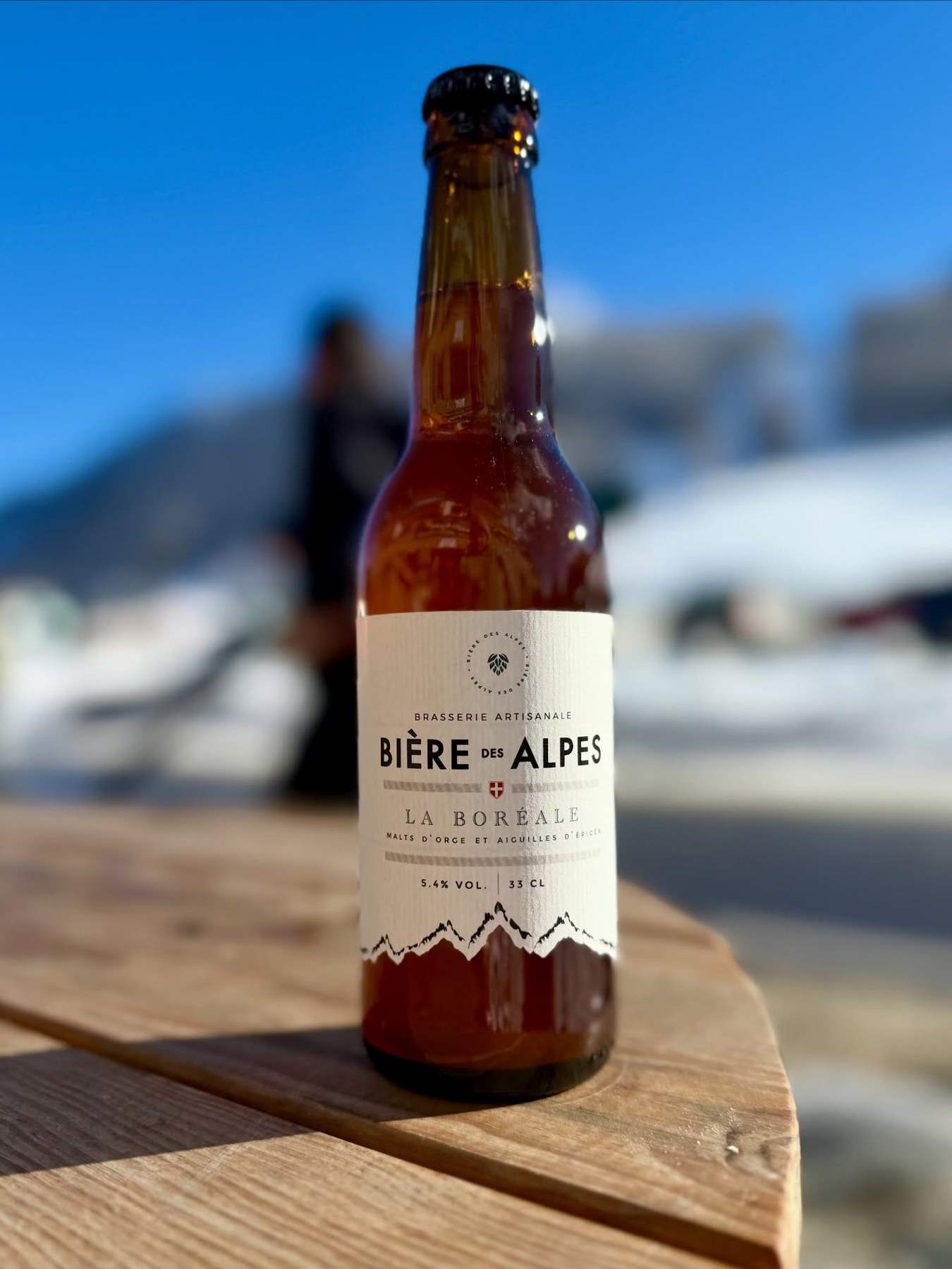 Une Bière des Alpes, La Boréale, sur une table en bois face aux pistes enneigées