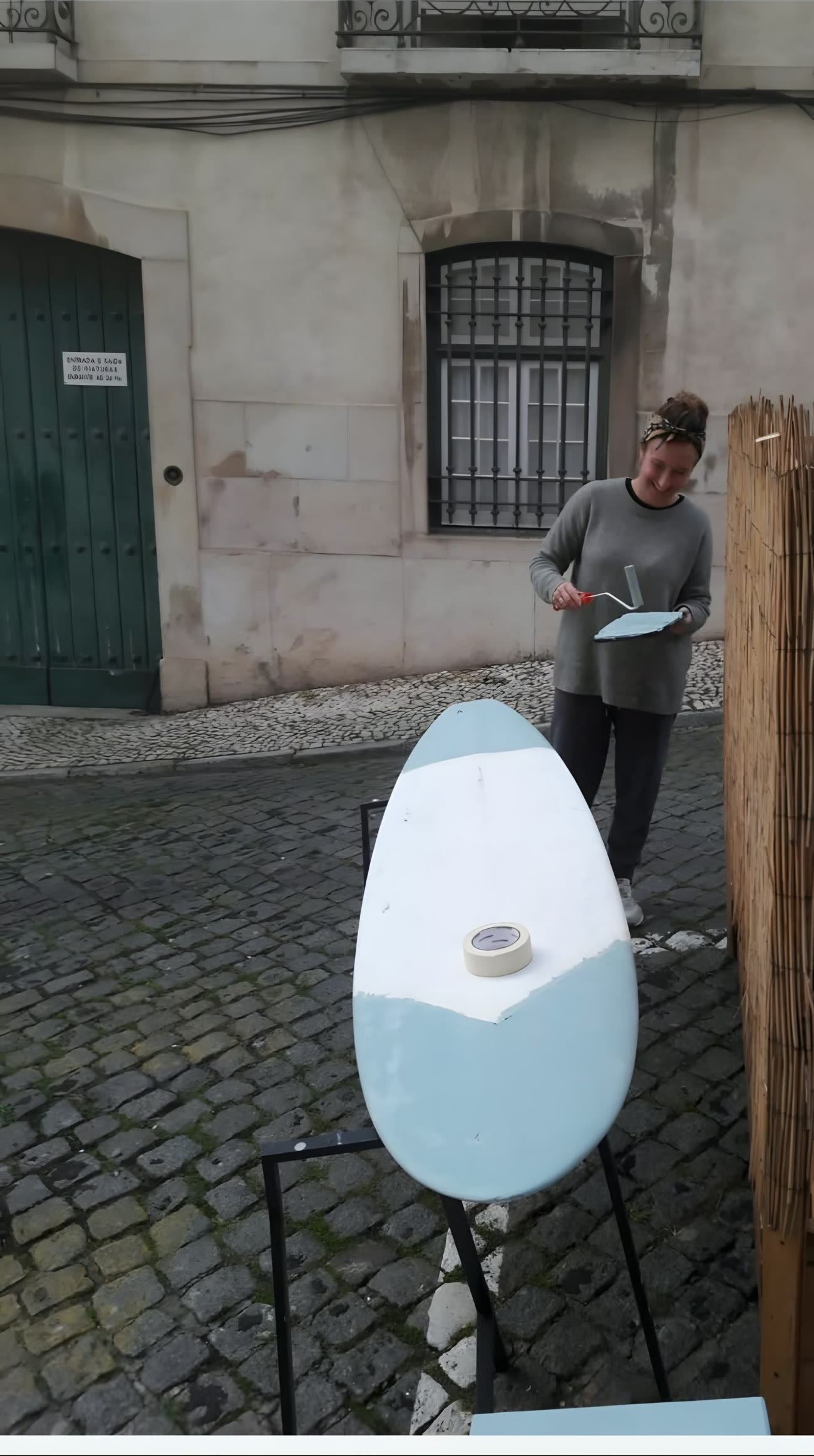 Laure installe l’enseigne d’un restaurant dans une ruelle pavée de Lisbonne