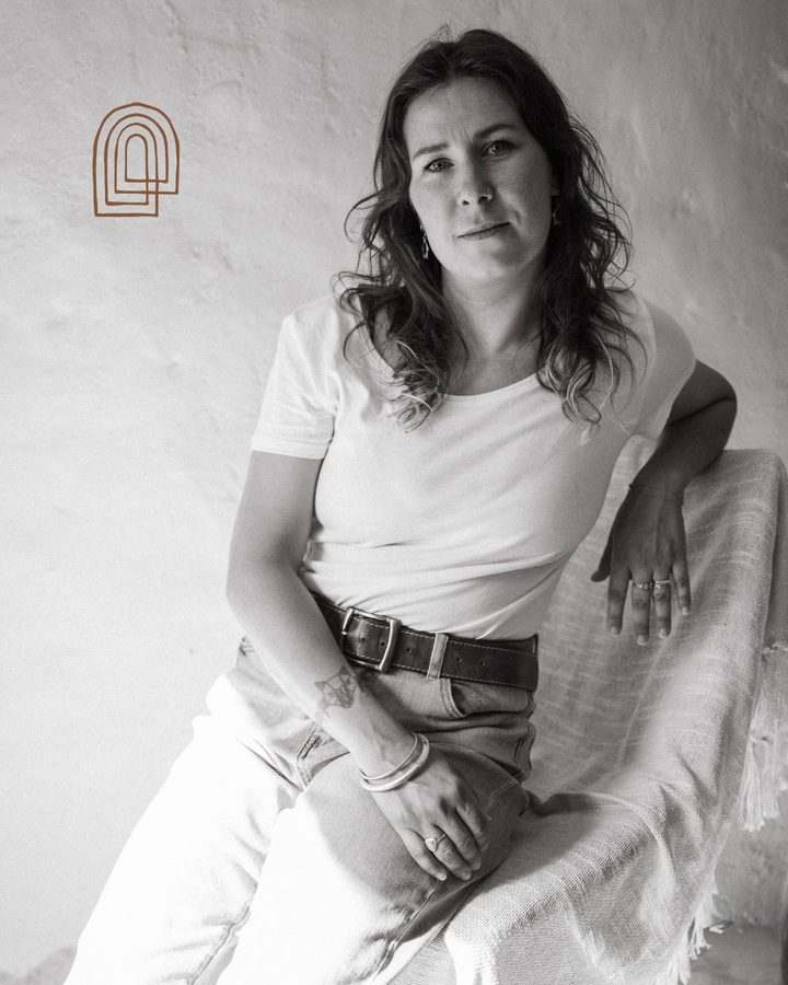 Laurine, en noir et blanc, assise contre un mur blanc