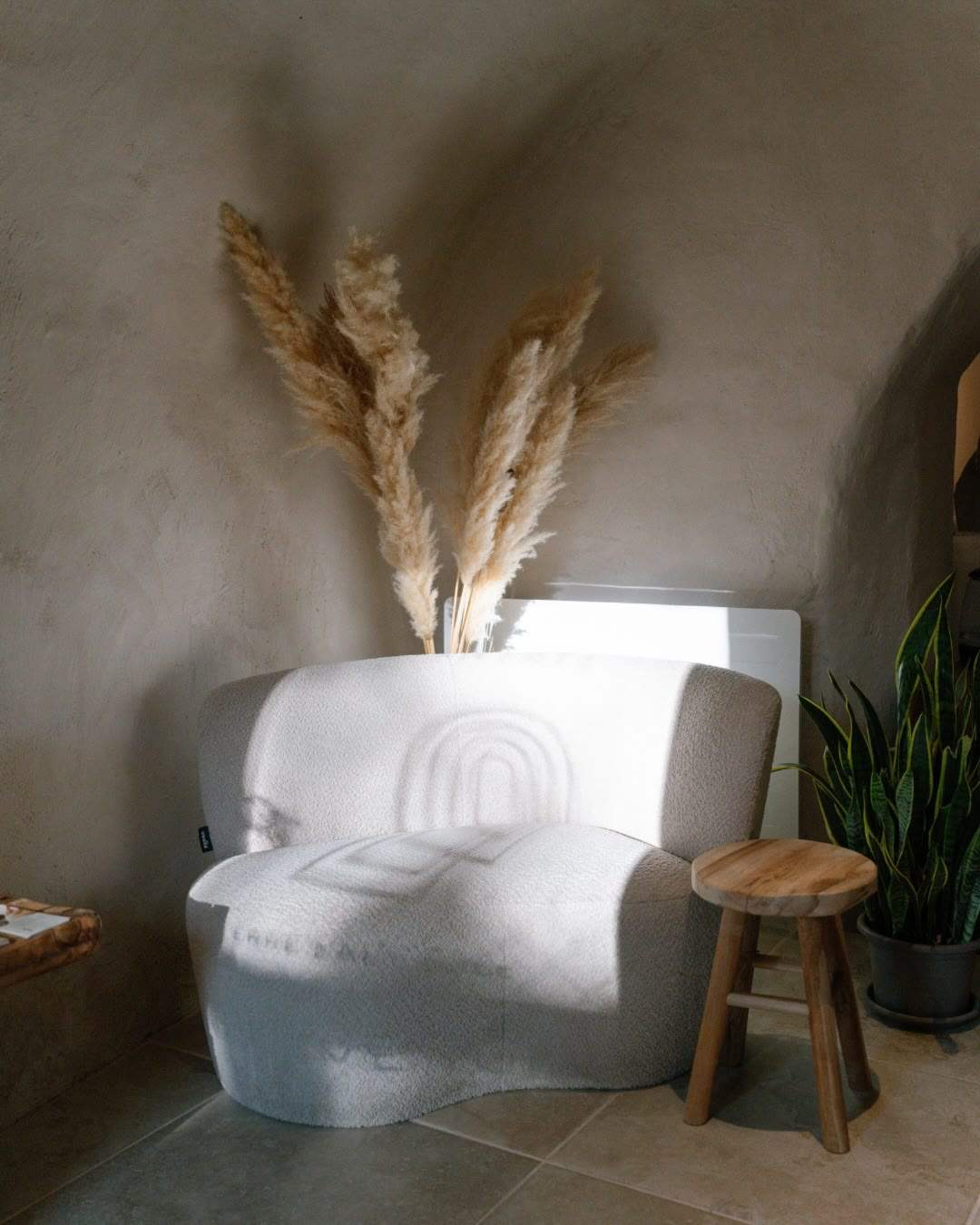 La lumière du matin sur un fauteuil clair brodé du logo de Terre d’Altitude, sous la voûte