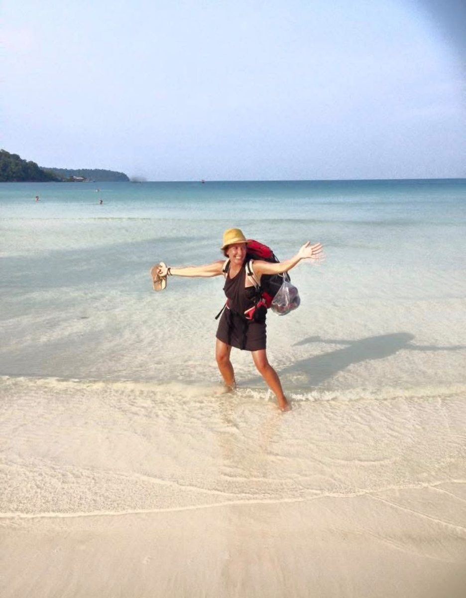 Laure sur une plage de sable blanc, les bras grands ouverts